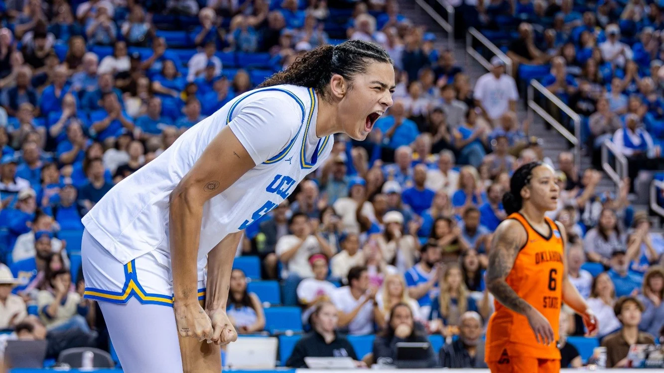 UCLA women's basketball player celebrating on court with an opponent nearby