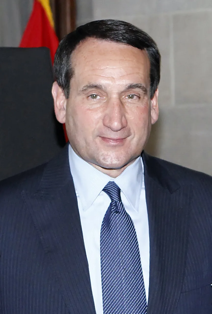 Mike Krzyzewski wearing a dark suit and blue tie