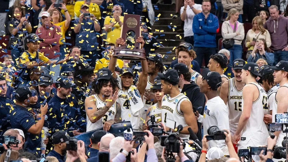 Michigan players raising a regional championship trophy amid confetti