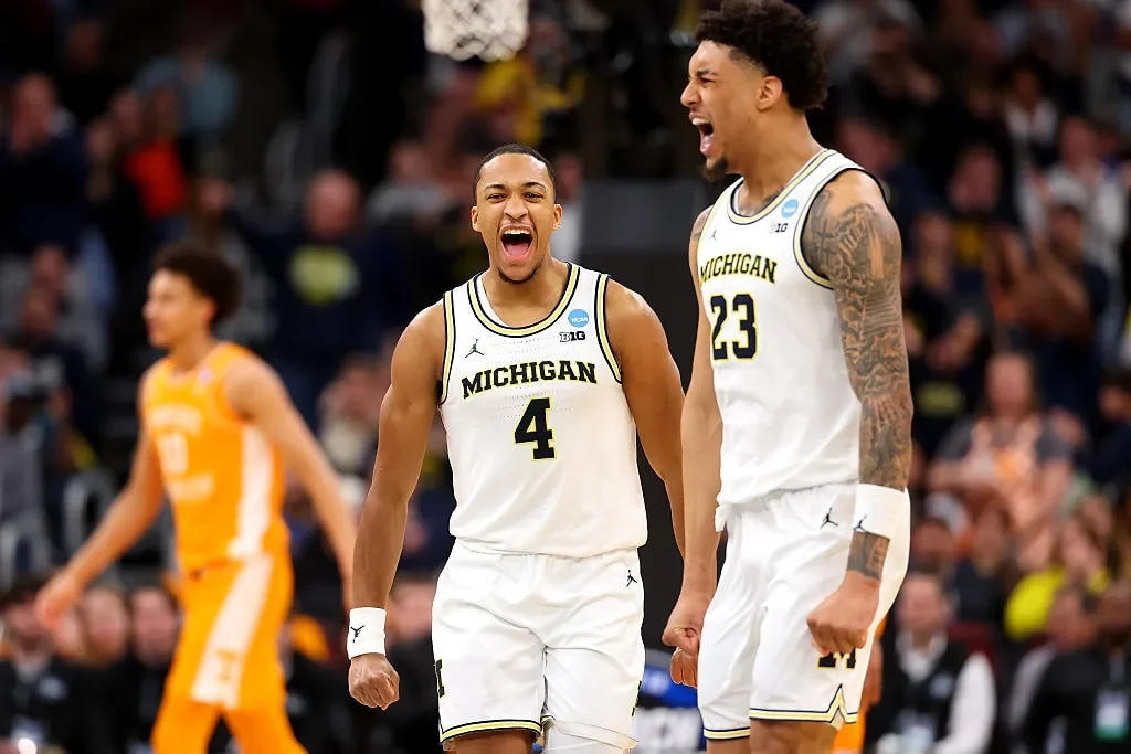 Two Michigan basketball players celebrating on the court