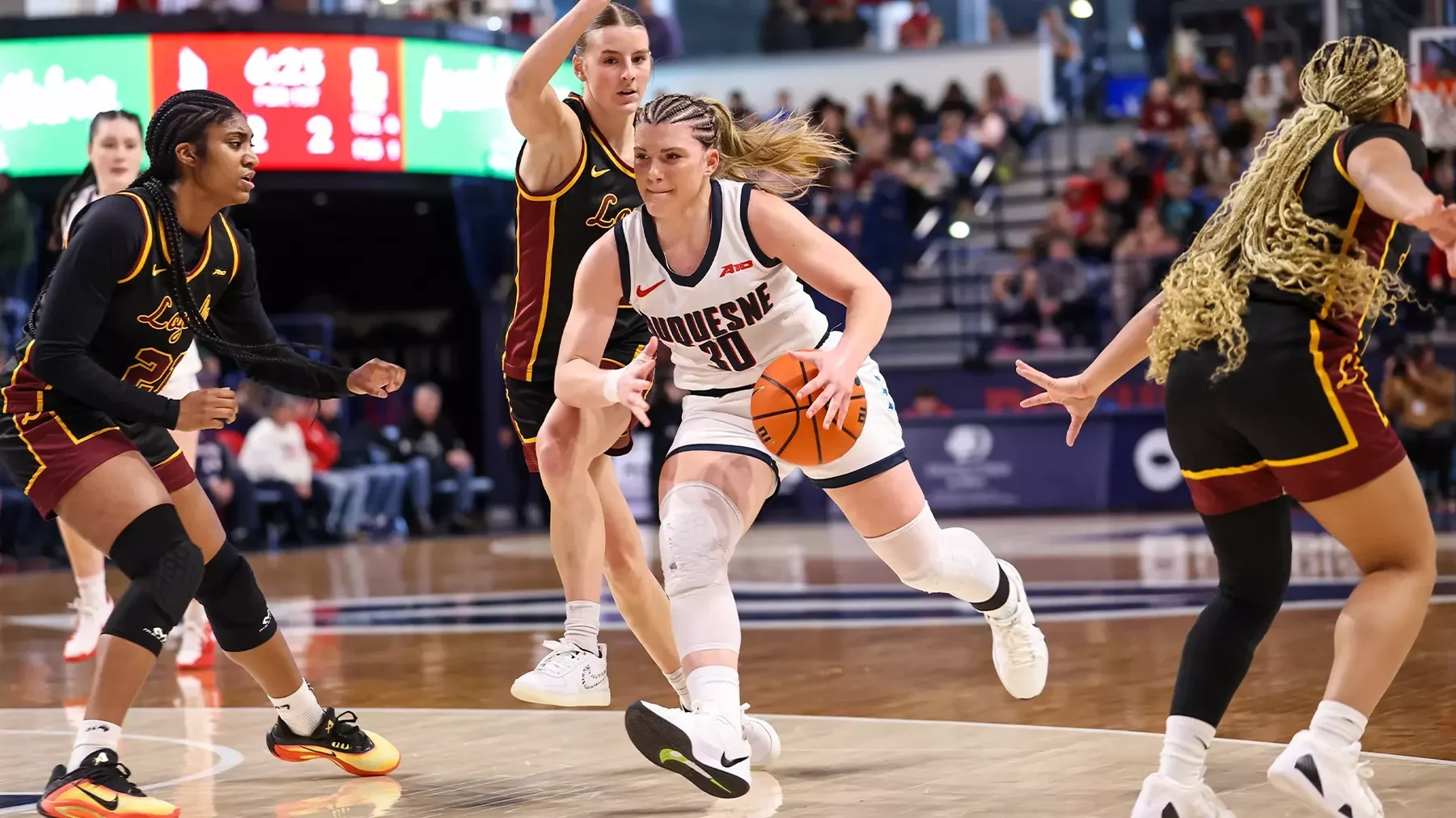 Duquesne ballhandler driving between Loyola Chicago defenders