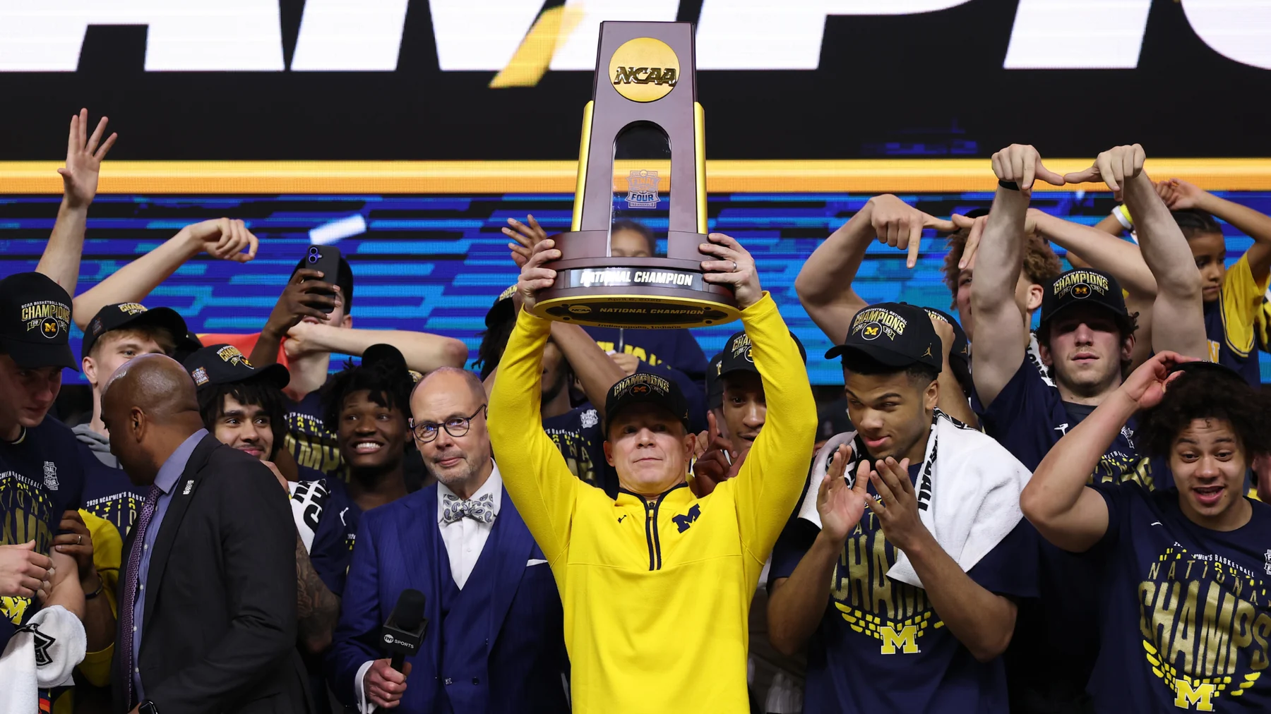 Men's college basketball team celebrating with a championship trophy