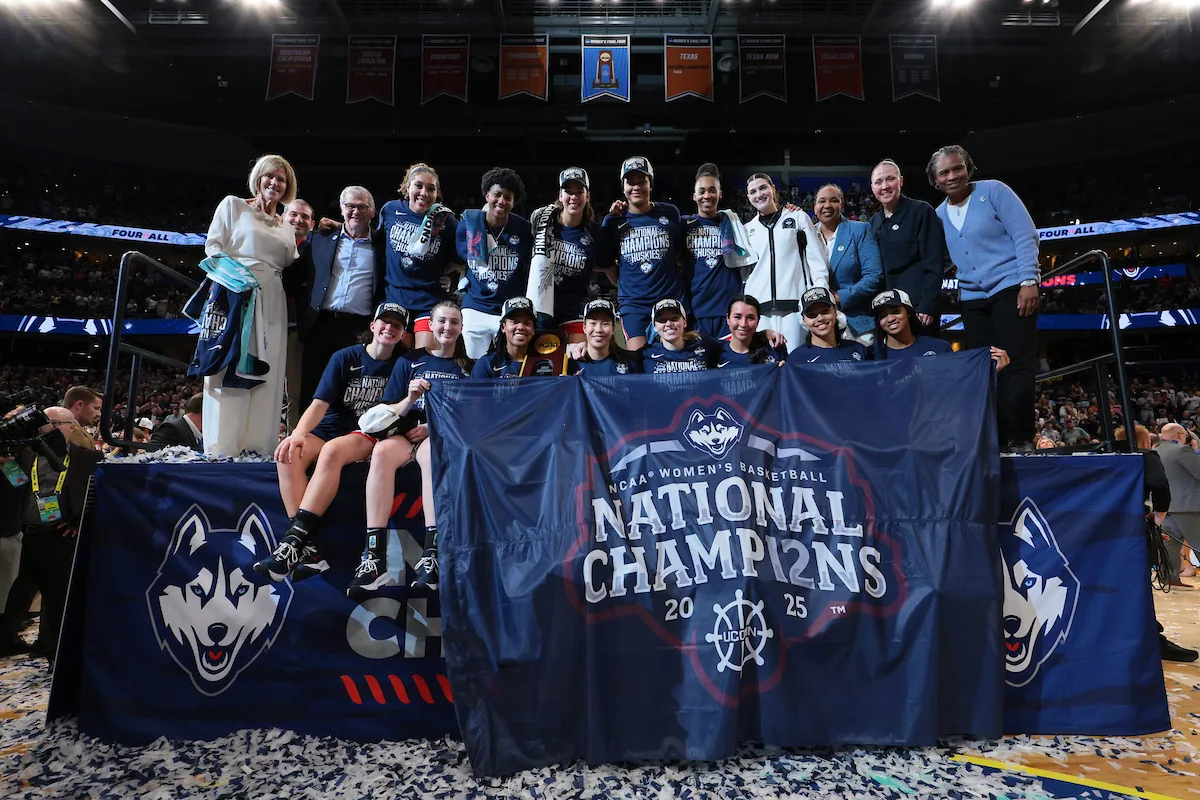 UConn women's basketball team poses behind a national champions banner